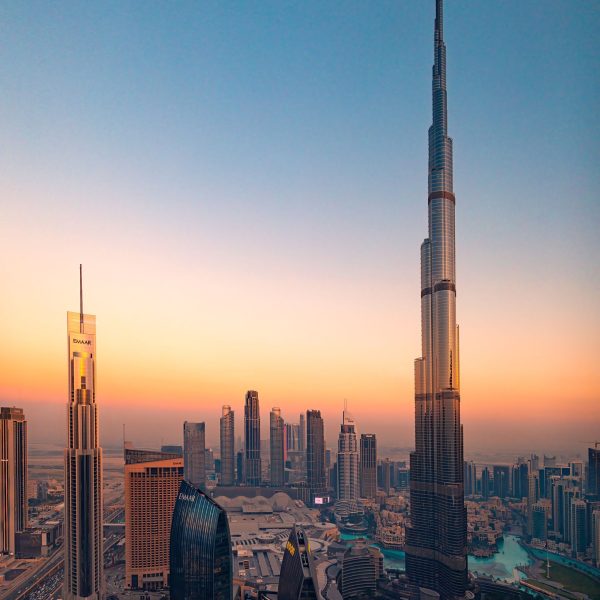 Aerial view of Burj Khalifa and Dubai skyline at sunset, showcasing modern skyscrapers and vibrant cityscape.
